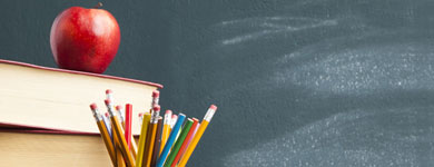 Image of Chalkboard, books, pencils in a cup and an apple.